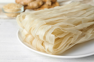 Photo of Raw rice noodles on white wooden table, closeup