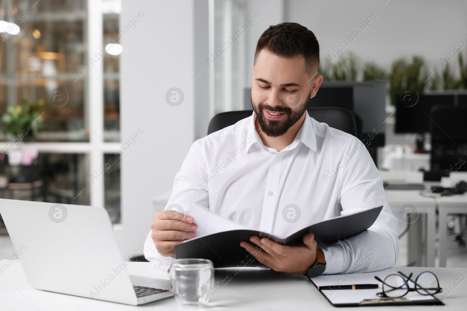 Photo of Smiling man working at table in office. Lawyer, businessman, accountant or manager