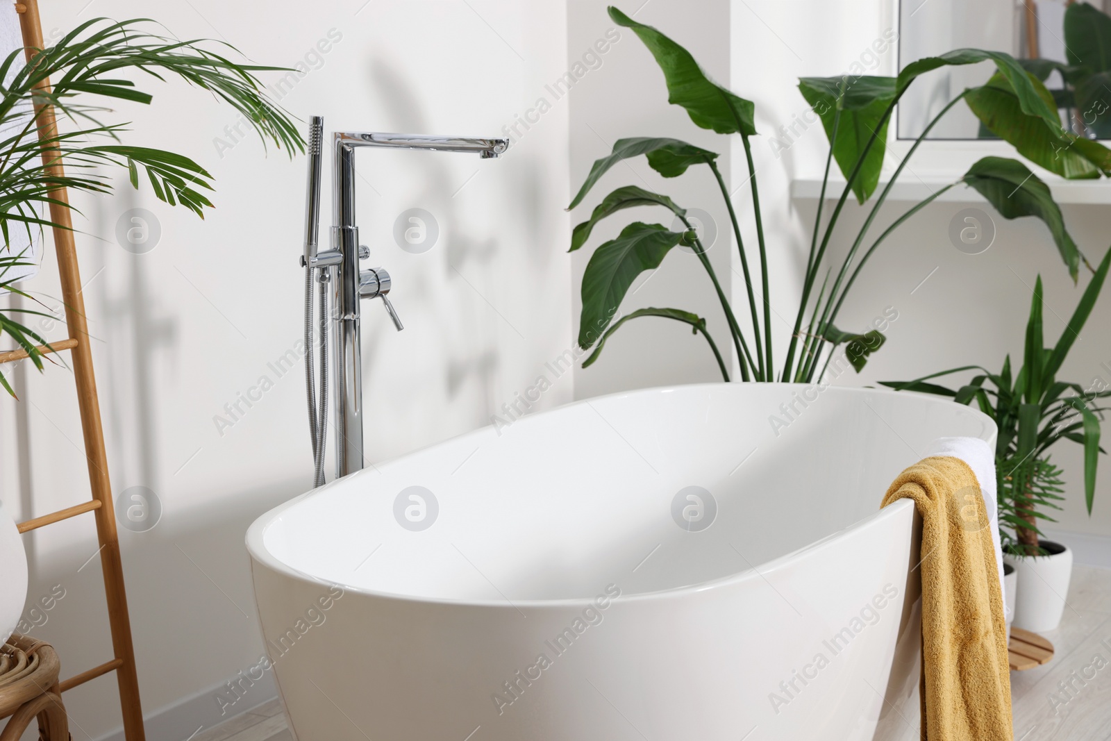 Photo of Stylish ceramic tub and beautiful houseplants in bathroom. Interior design