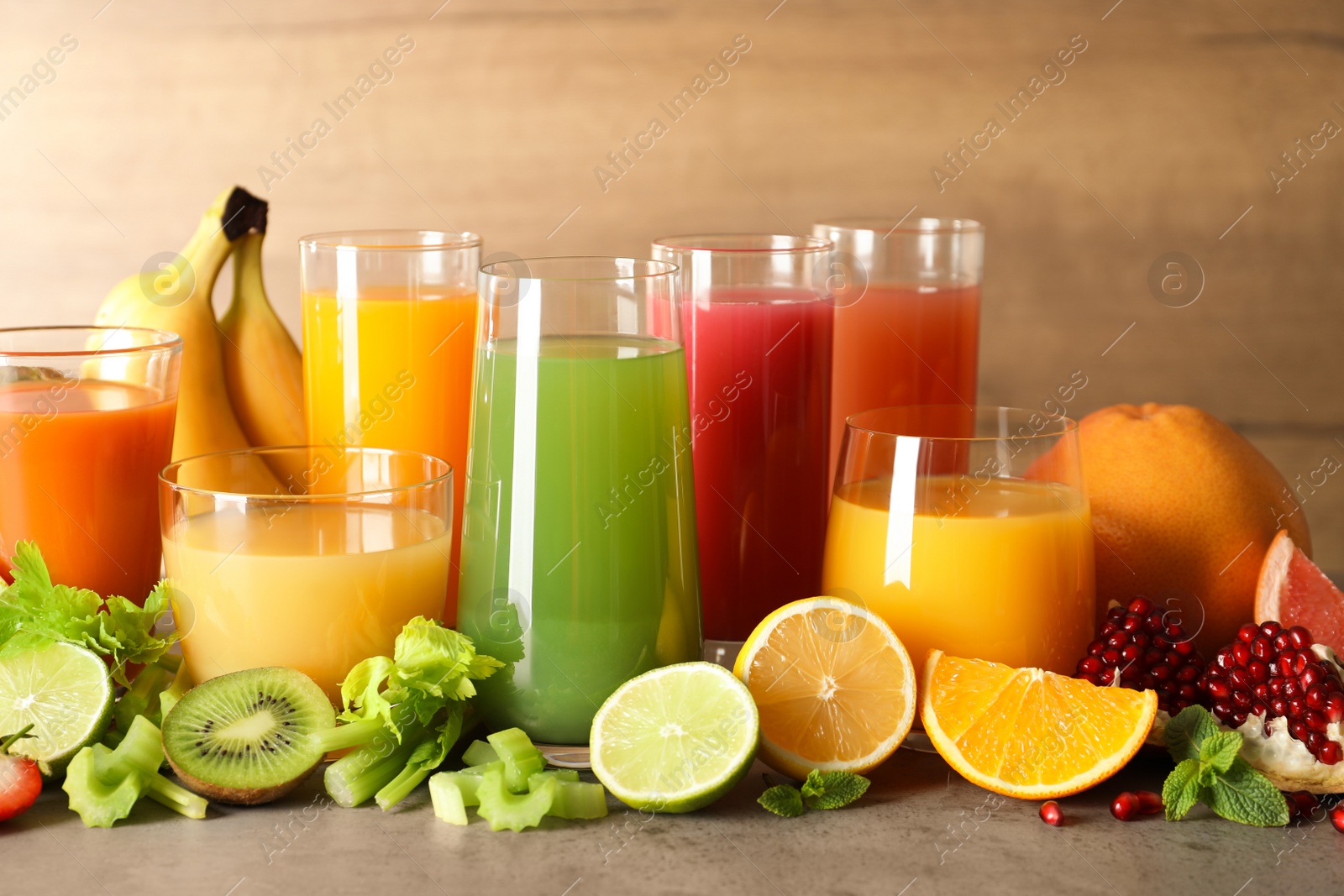 Photo of Glasses with different juices and fresh fruits on table