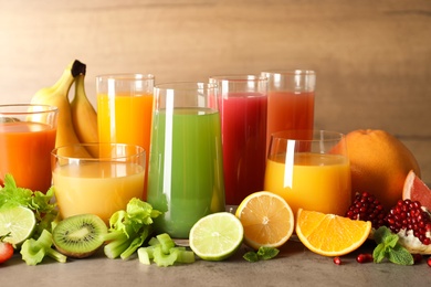 Photo of Glasses with different juices and fresh fruits on table