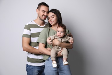 Photo of Happy family. Couple with their cute baby on grey background, space for text