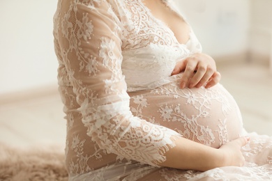 Young pregnant woman in elegant dress at home