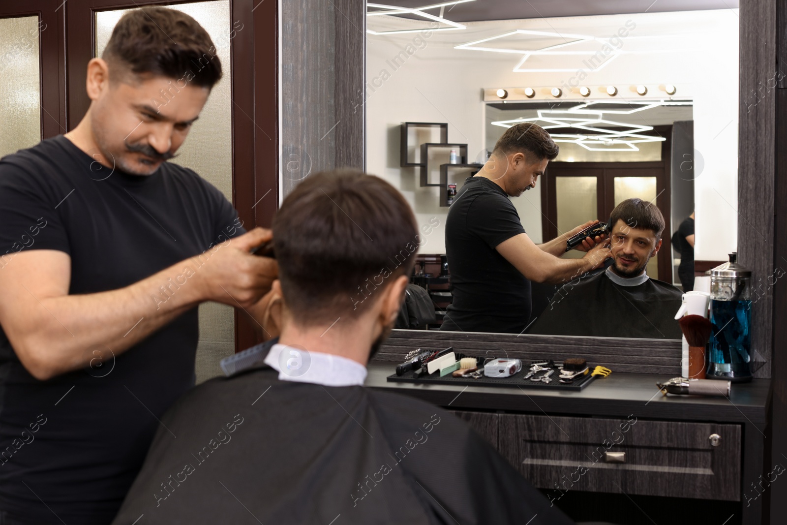 Photo of Professional hairdresser making stylish haircut in barbershop