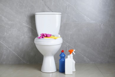 Photo of Toilet bowl and different cleaning supplies indoors