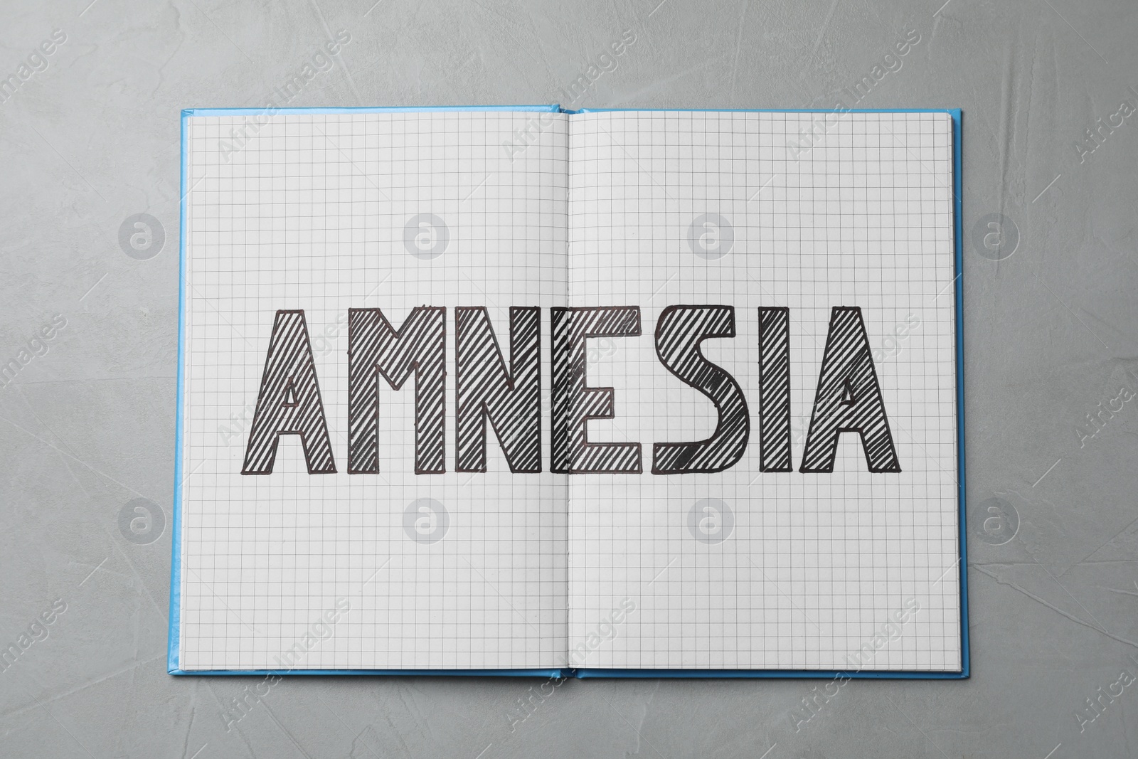 Photo of Notebook with word Amnesia on light grey table, top view