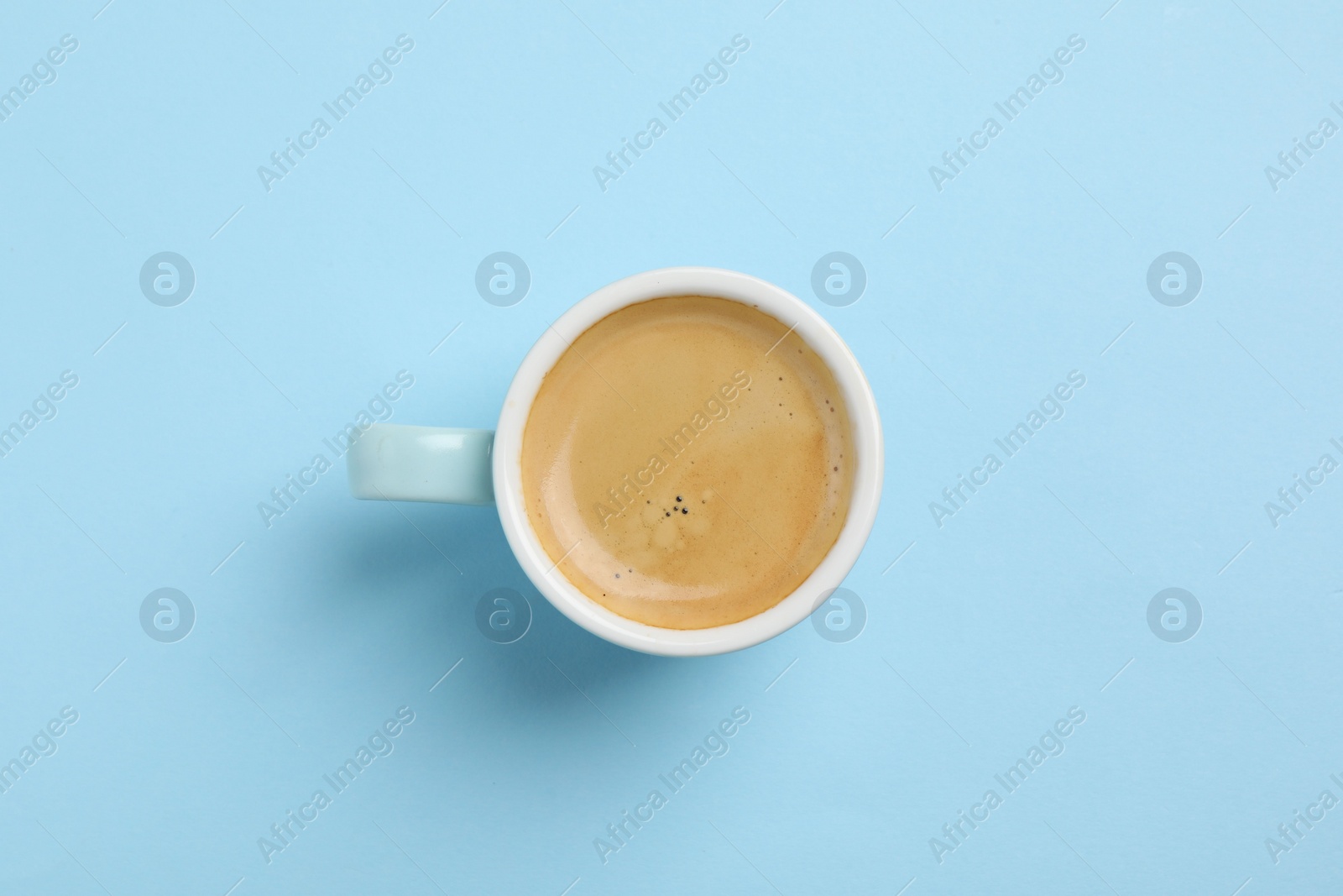 Photo of Aromatic coffee in cup on light blue background, top view