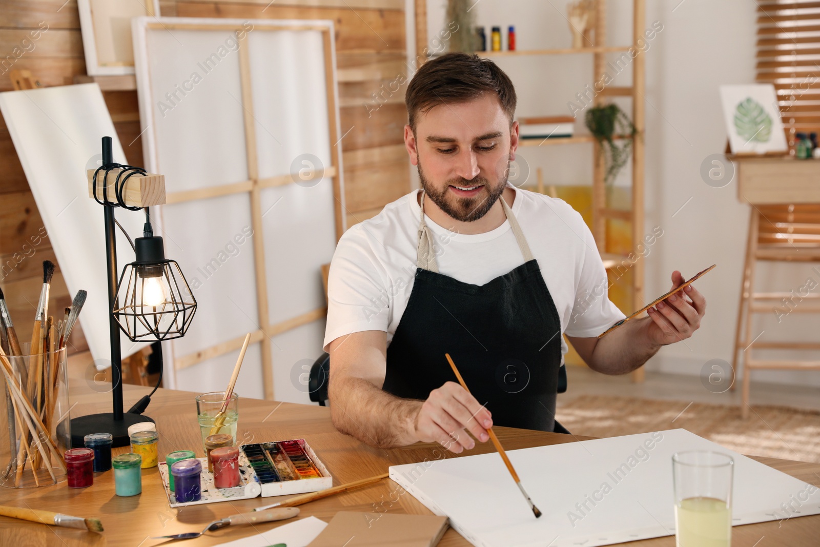 Photo of Young man painting with brush in artist studio