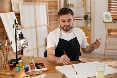 Young man painting with brush in artist studio