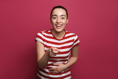 Photo of Beautiful young woman laughing on maroon background. Funny joke