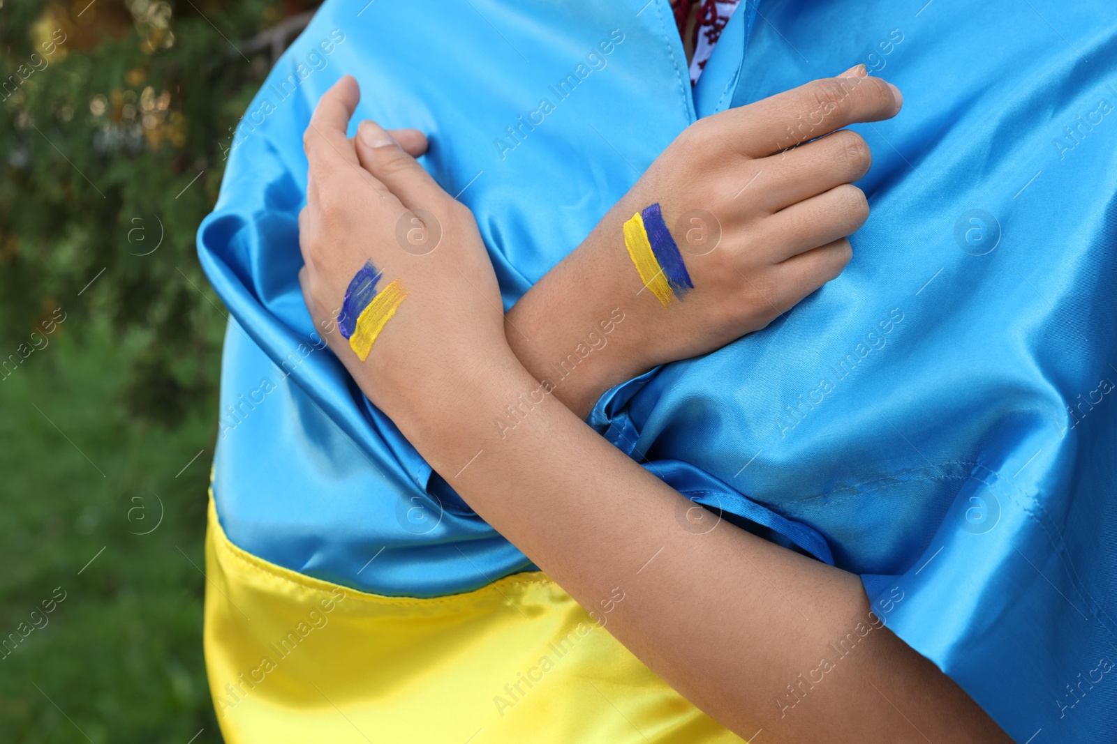 Photo of Woman with drawings of Ukrainian flag on hands outdoors, closeup