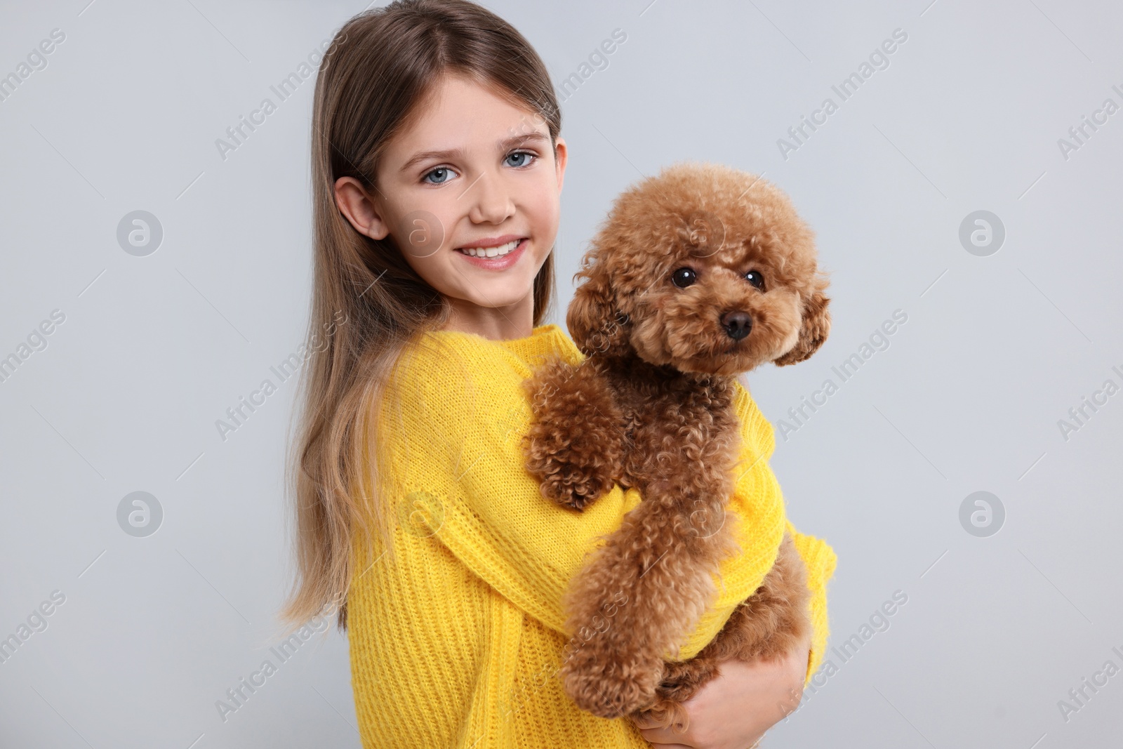 Photo of Little child with cute puppy on light grey background. Lovely pet