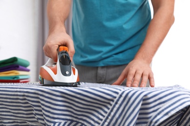 Photo of Man ironing shirt on board at home, closeup