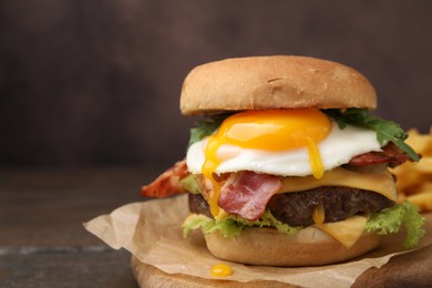 Photo of Delicious burger with fried egg on wooden table, closeup. Space for text