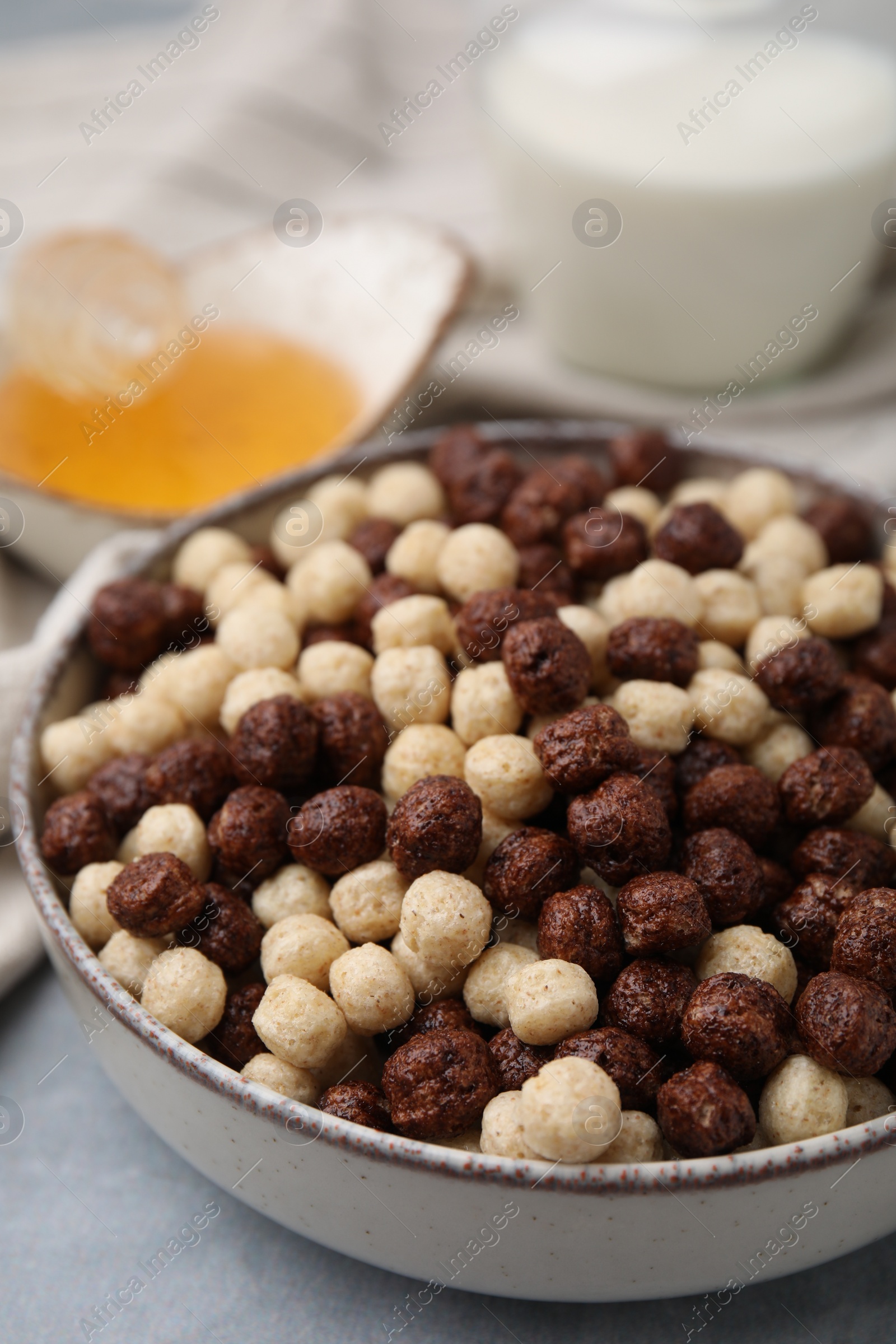 Photo of Tasty cereal balls in bowl on grey table, closeup