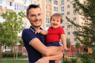 Photo of Father with adorable little baby outdoors. Happy family