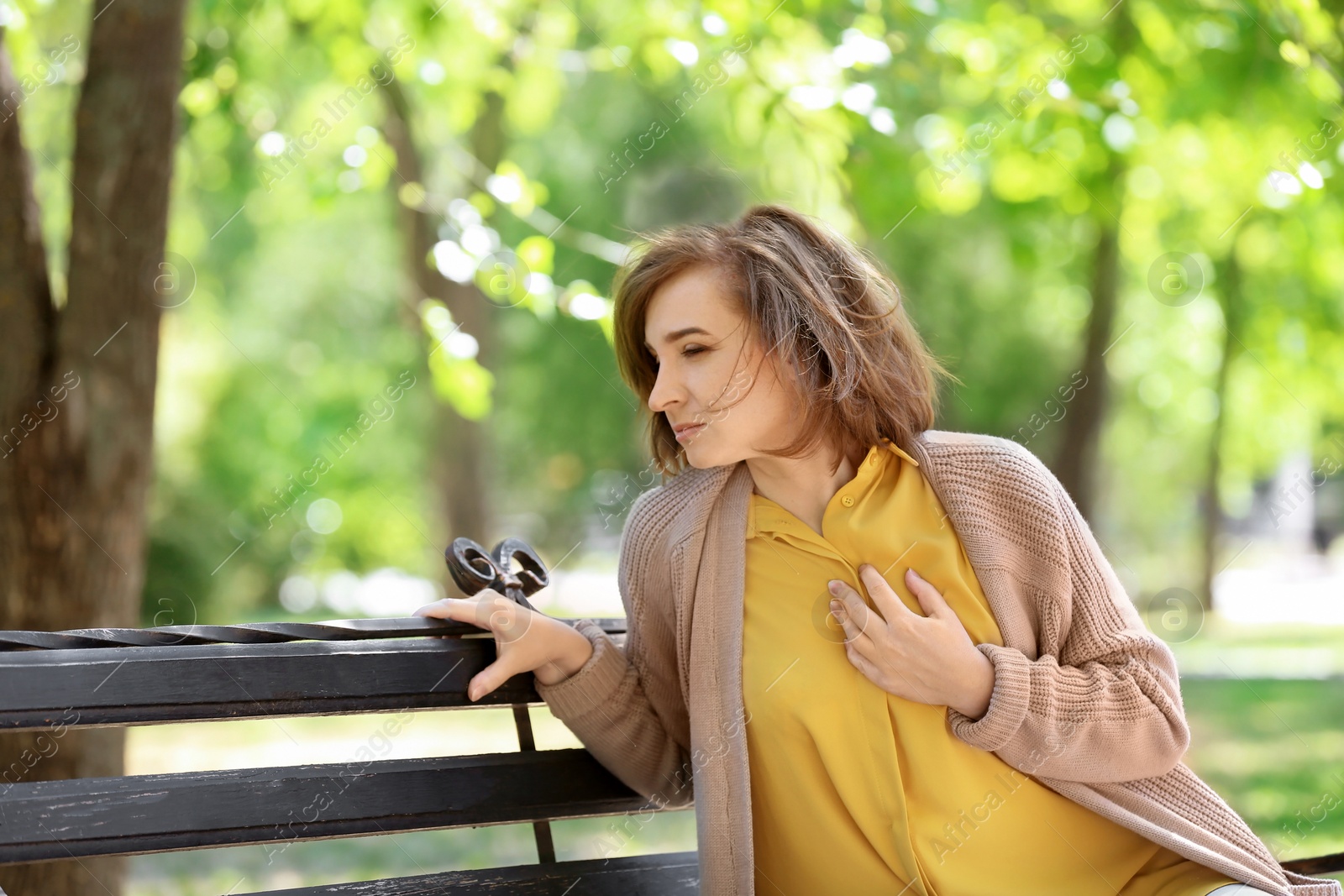 Photo of Mature woman having heart attack on bench in park