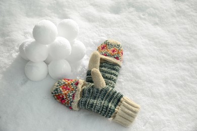 Photo of Knitted mittens and snowballs on snow outdoors