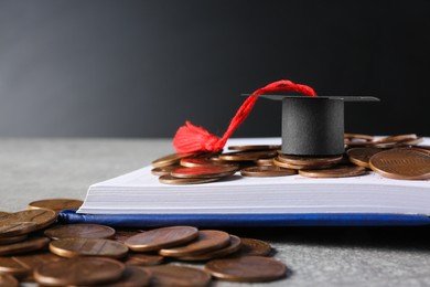 Photo of Scholarship concept. Graduation cap, notebook and coins on light grey table, closeup
