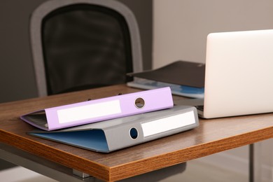Photo of File folders near laptop on wooden table in office