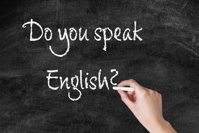 Image of Woman writing question DO YOU SPEAK ENGLISH on blackboard, closeup