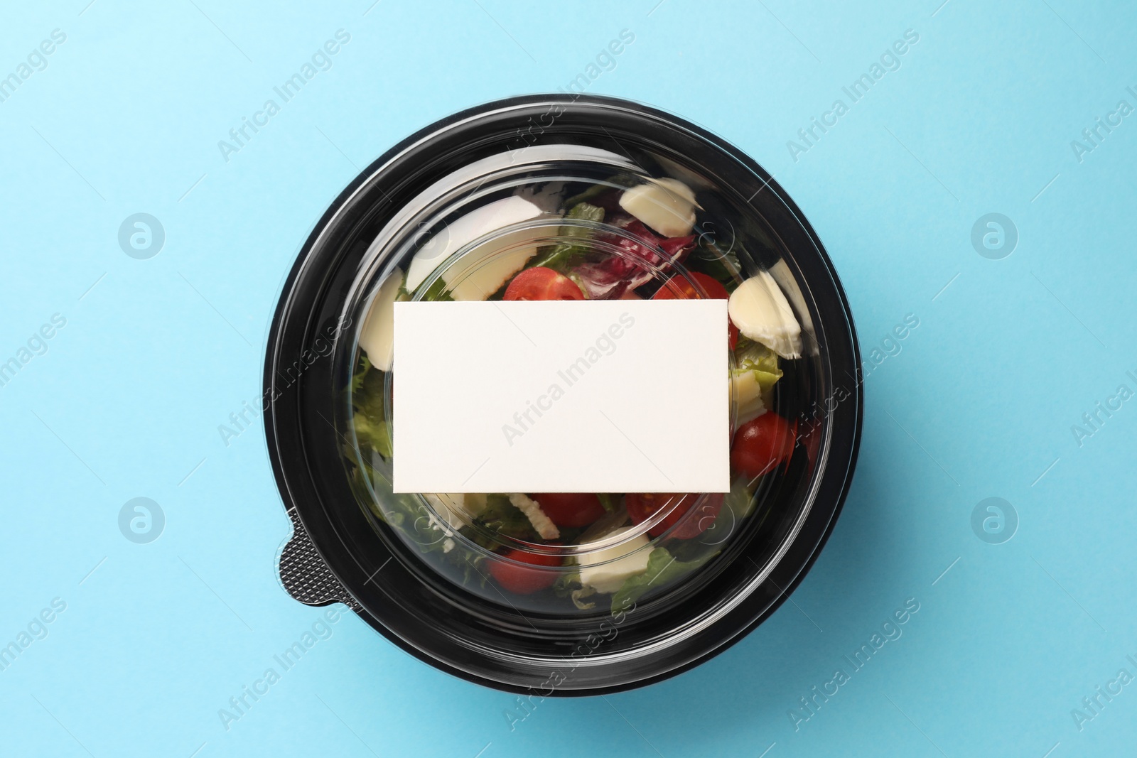 Photo of Tasty food in container on light blue background, top view. Space for text