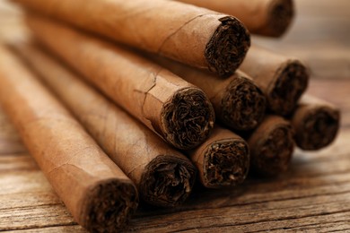 Cigars wrapped in tobacco leaves on wooden table, closeup