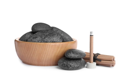 Incense stick smoldering near spa stones on white background