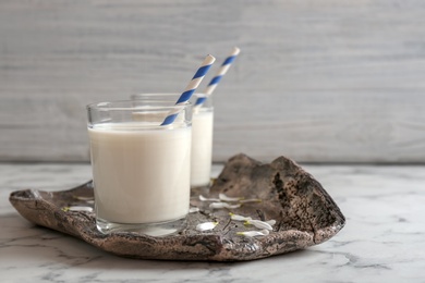 Glasses of milk with straws on plate