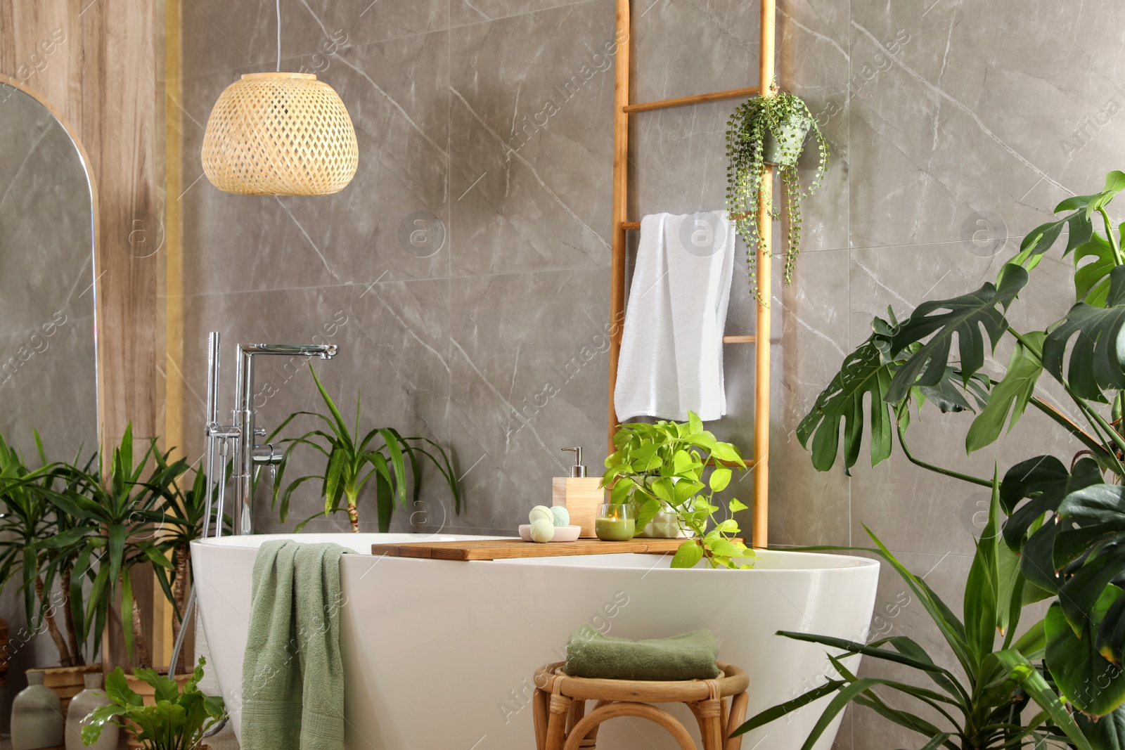 Photo of Modern white tub and beautiful green houseplants in bathroom. Interior design