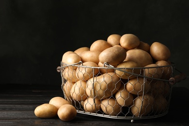 Raw fresh organic potatoes on wooden table against dark background