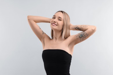 Portrait of beautiful tattooed woman on light background