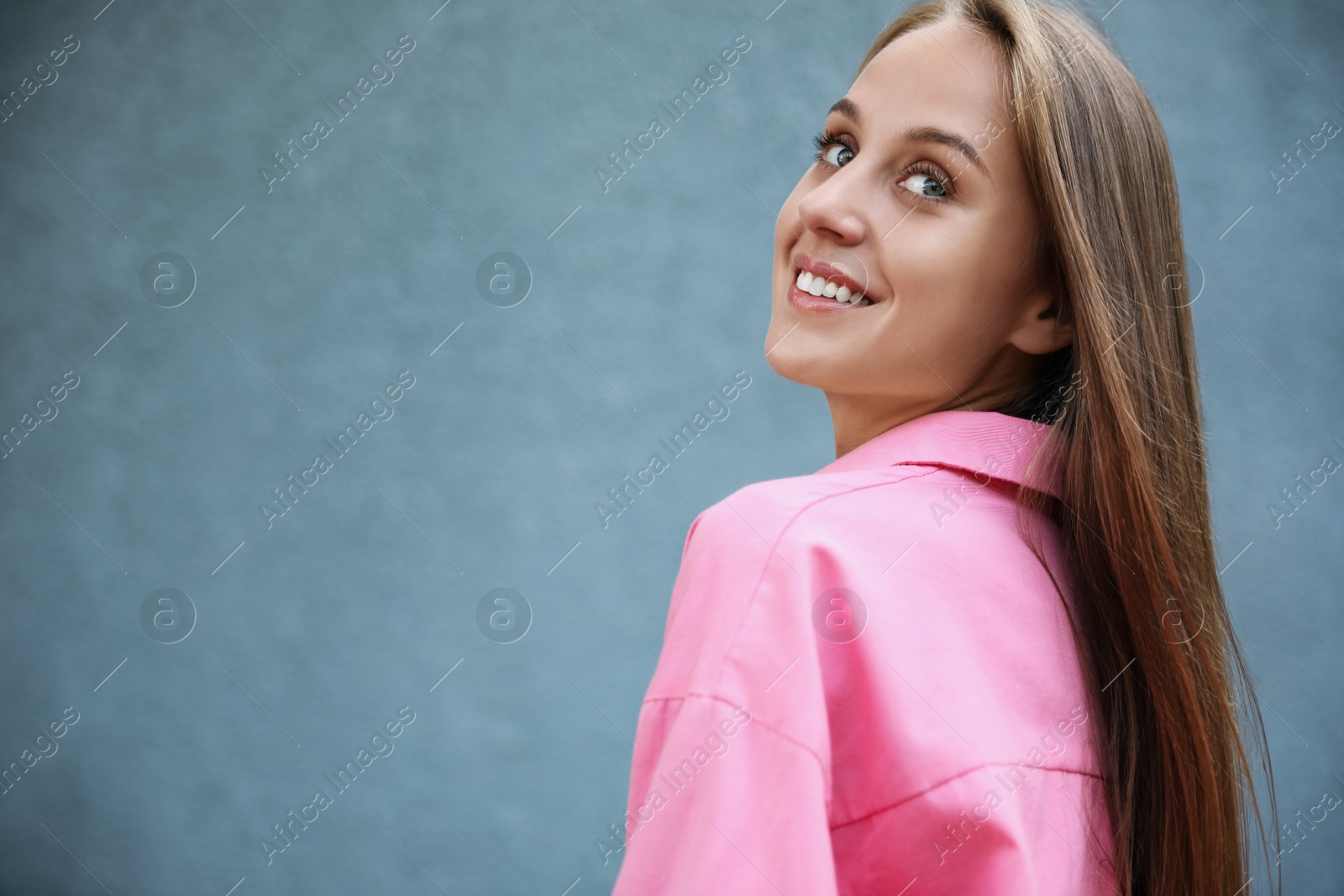 Photo of Beautiful young woman near grey wall, space for text