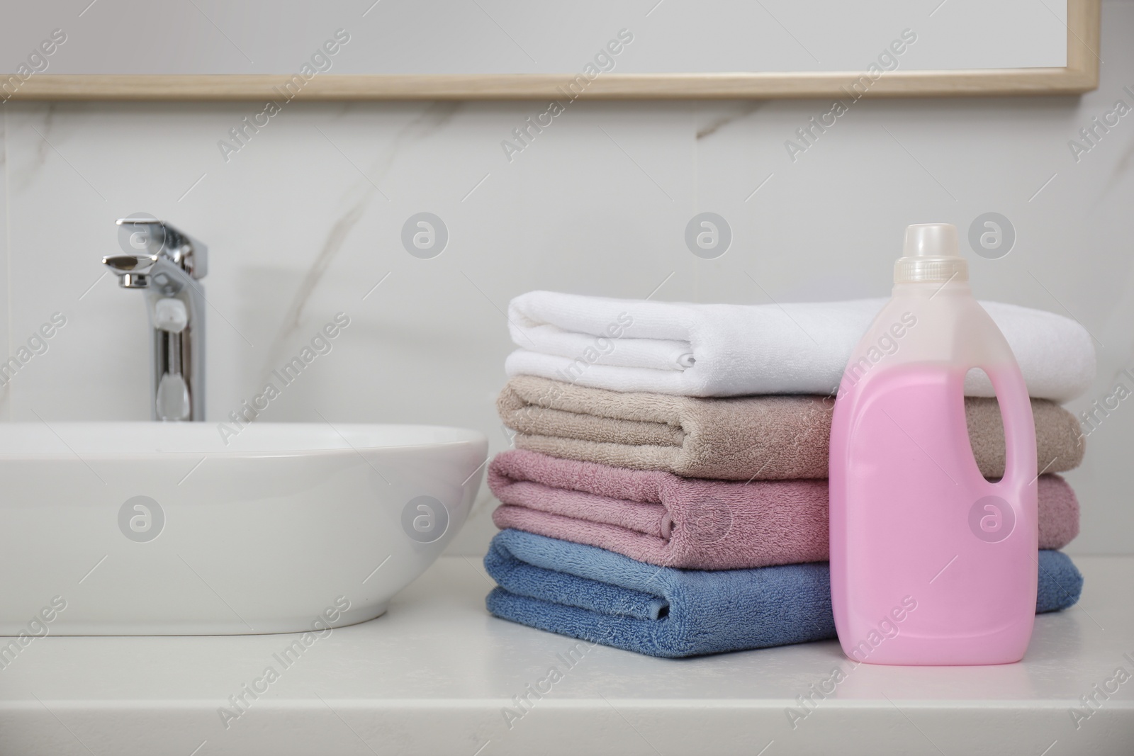 Photo of Stack of fresh towels and detergent in laundry room