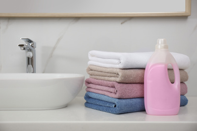 Stack of fresh towels and detergent in laundry room