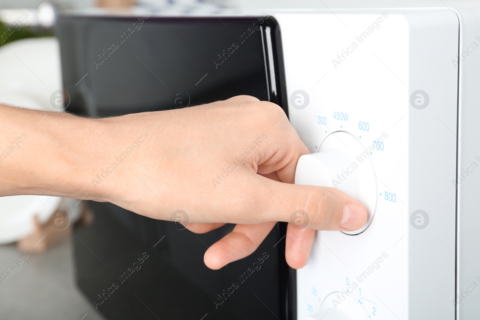 Photo of Woman adjusting microwave oven in kitchen, closeup