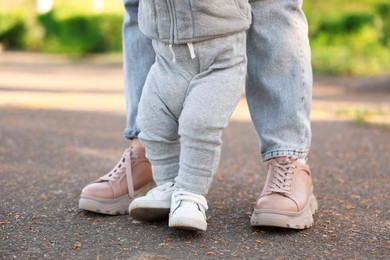 Photo of Mother teaching her baby how to walk outdoors, closeup