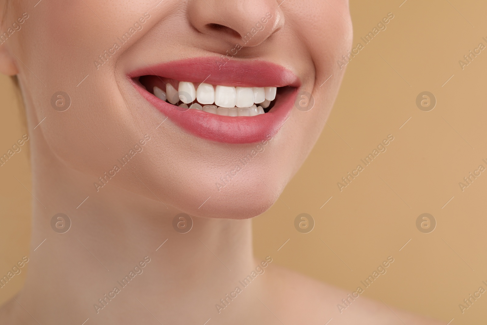 Photo of Young woman with beautiful smile on beige background, closeup