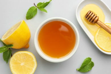 Sweet honey and fresh lemon on white table, flat lay