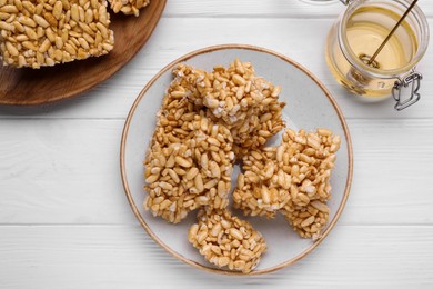 Puffed rice bars (kozinaki) and honey on white wooden table, flat lay