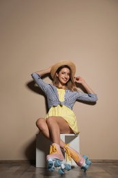 Photo of Young woman with retro roller skates against color wall. Space for text