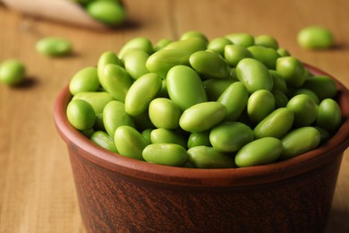 Photo of Bowl of delicious edamame beans on wooden table, closeup