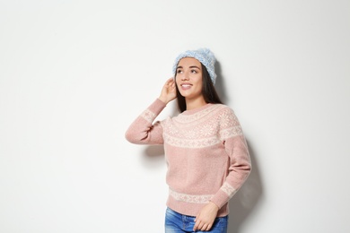 Photo of Young woman in warm sweater and knitted hat on white background. Celebrating Christmas