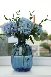 Photo of Beautiful blue hortensia flowers in vase on window sill indoors