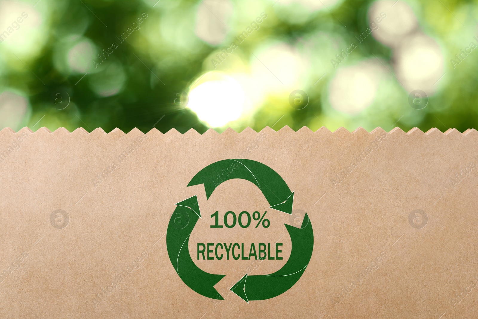 Image of Paper bag with recycling symbol on blurred green background. Eco friendly package