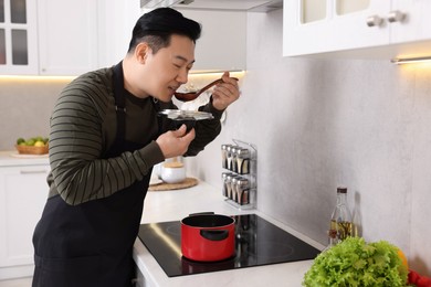 Cooking process. Man tasting dish in kitchen