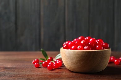 Tasty ripe cranberries on brown wooden table, closeup. Space for text