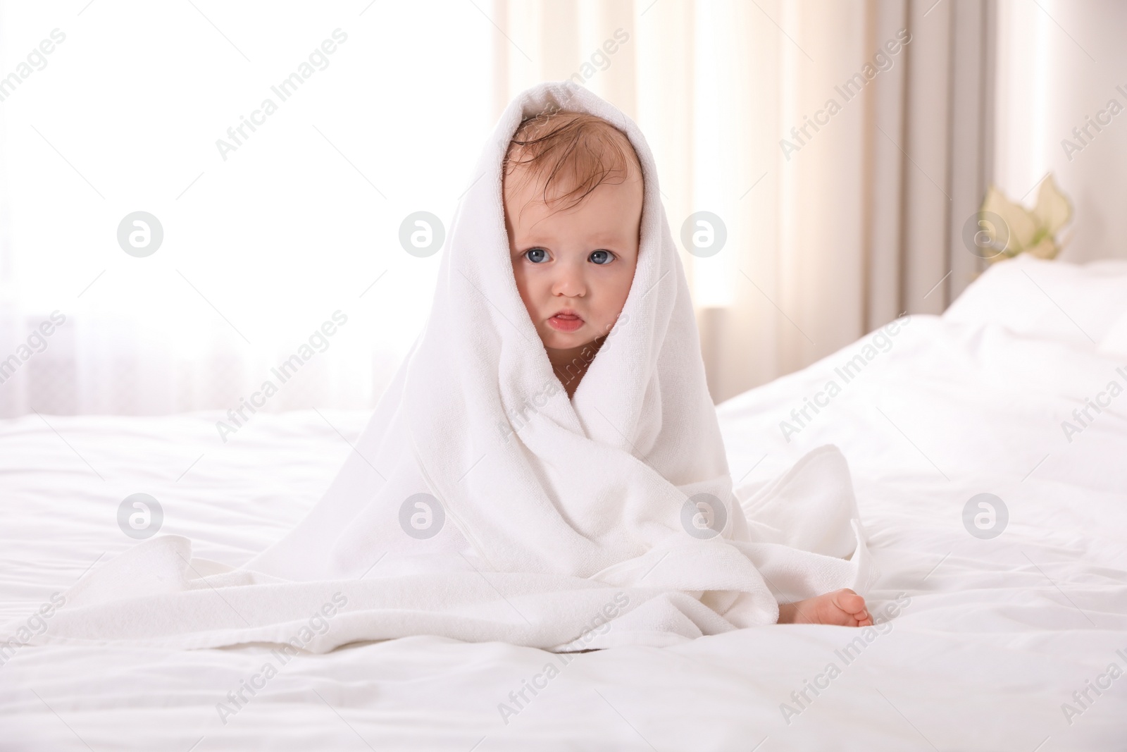 Photo of Cute little baby with soft towel on bed after bath