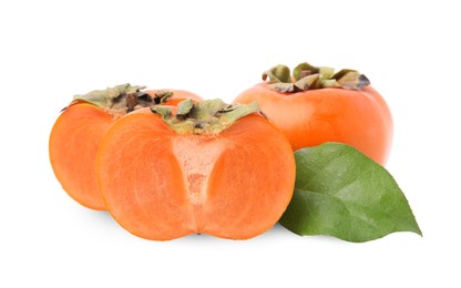 Photo of Whole and cut delicious ripe juicy persimmons with green leaf on white background