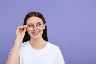 Photo of Smiling woman in stylish eyeglasses on violet background. Space for text